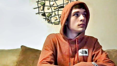 Young Latino man in orange hoodie, intense side gaze, gay amateur solo