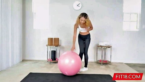 Fit blonde Allie Addison in sports bra and tight pants posing with exercise ball