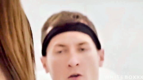 White guy in black headband with open mouth and brunette hair in close-up threesome scene