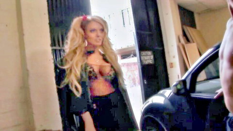 Blonde babe with big pierced tits in sheer top teases in garage with muscular stud arm around her