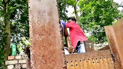 South Asian man climbing rusty metal outdoors in red shirt, gutpunch setup