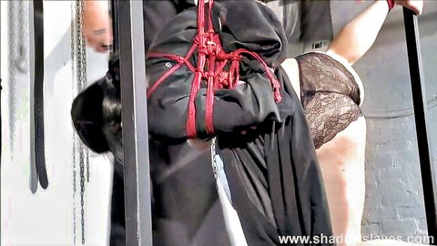 Submissive Asian woman in red rope suspension bondage with lace panty ass exposed by dominant man