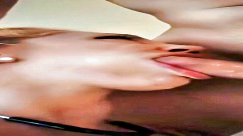 Blonde woman with tongue out sucking thick black cock in intense close-up blowjob.