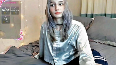 Goth girl with silver hair teases cleavage in open satin shirt on webcam bed