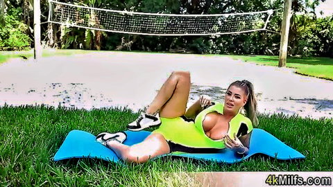 Busty Lolly Dames poses seductively in neon green bodysuit on yoga mat outdoors