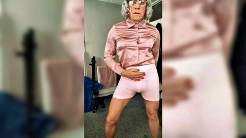 Crossdressed grandma in pink satin blouse and white shorts with visible bulge