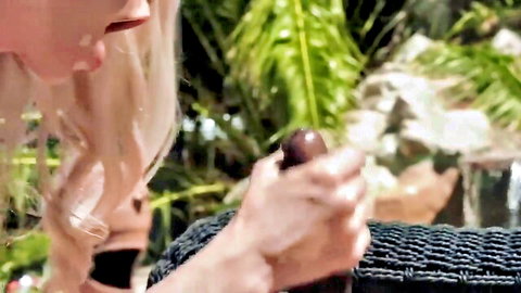 Blonde with long hair grips thick dark cock in hand, open mouth ready to suck outdoors