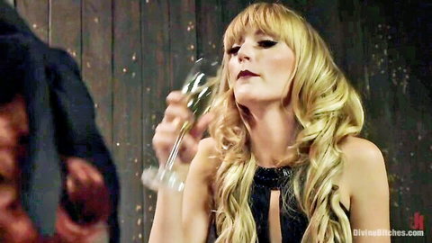 Seductive blonde mistress in revealing black dress sips champagne exposing deep cleavage