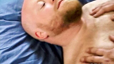 Bald bearded man lying relaxed with hand caressing chest in gentle intimate scene