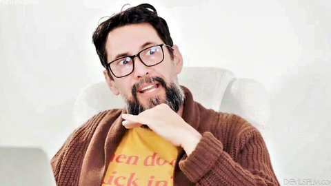 Tommy Pistol, handsome bearded man in glasses, casual pose on sofa