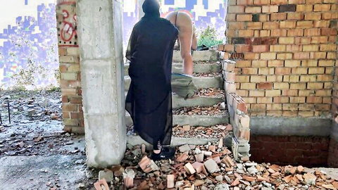 Veiled Arab mistress in black abaya stands over naked blonde's exposed ass on outdoor ruined stairs