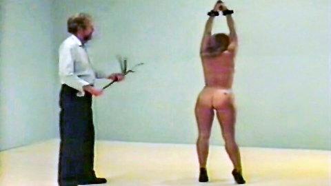Bound nude woman whipped by man in BDSM scene