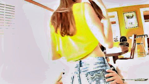 Erotic brunette in skimpy yellow crop top and low-rise jeans bending over
