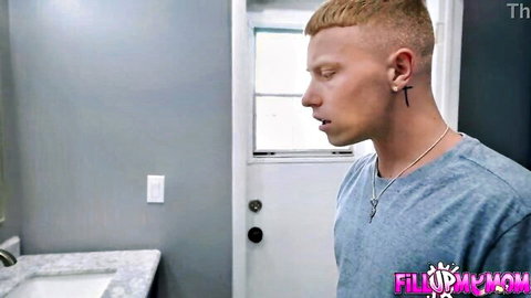 Young blonde stud in gray shirt, serious expression in MILF banging adult scene