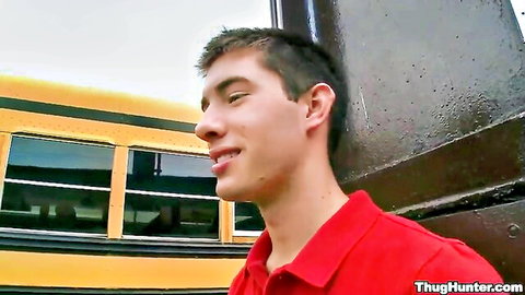 Young Latino guy in red polo shirt leaning on school bus, gay porn teaser