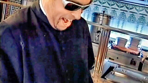 Sunglasses-wearing priest in black clerical attire smiling in kitchen for raunchy MILF scene