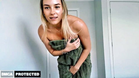 Blonde babe smiling seductively clutching green towel over her tits and pussy in bathroom tease