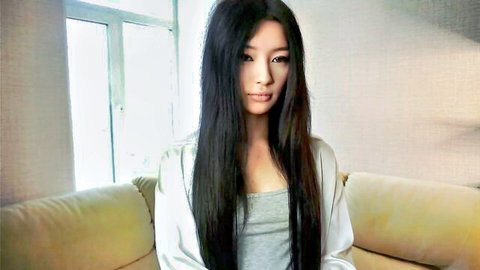 Young Asian beauty in open silk robe showing deep cleavage on couch
