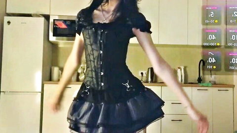 Sexy goth girl in tight black corset and frilly mini skirt dancing teasingly in kitchen on webcam