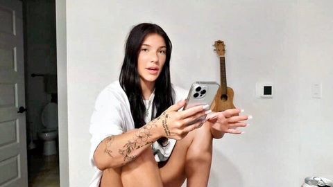 Fit brunette in white shirt holding ukulele and phone, casual pose