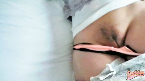 Daddys Luder pulls pink panties aside, exposing intimate area on bed