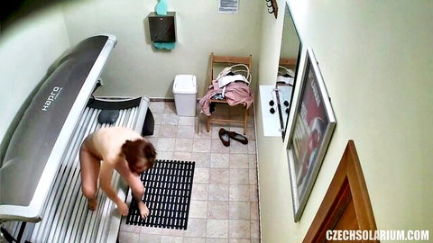 Hairy MILF squatting nude in solarium, exposing bushy pussy