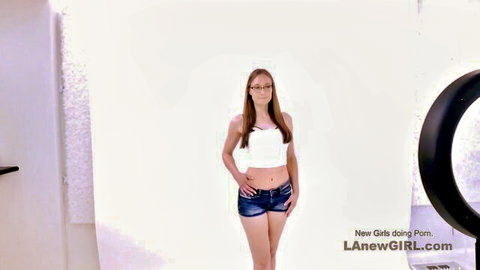 Redhead amateur in white tank top and denim shorts posing in studio