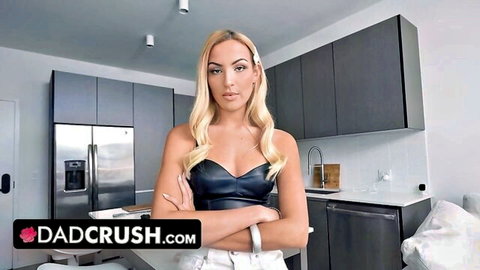 Hot blonde babe in tight leather top crosses arms showing cleavage in kitchen