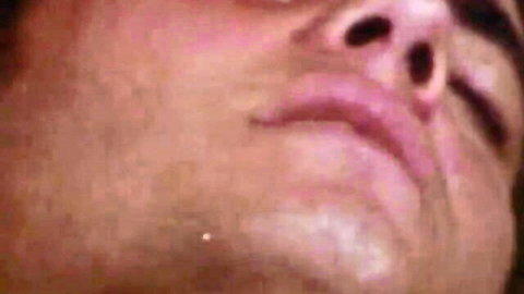 Close-up of man's stubbled face with pursed lips and flared nostrils during intense oral pleasure