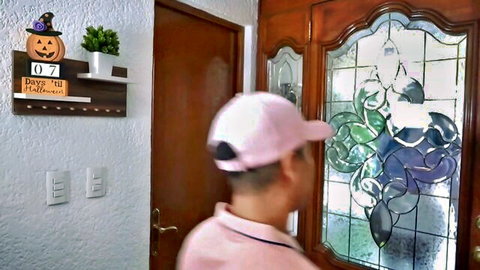 Mei Cornejo in pink cap entering Halloween-decorated home door