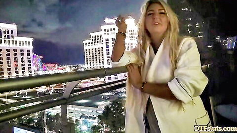 Blonde in white jacket on Vegas balcony, teasing night view