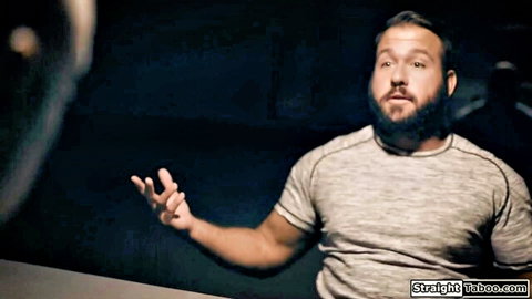 Bearded man in gray t-shirt gesturing intensely, dark setting