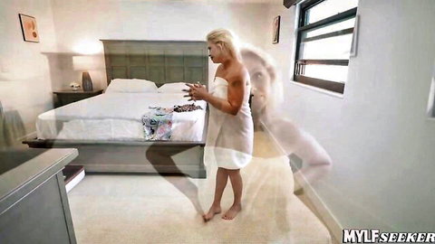 Blonde MILF in white robe, teasing pose in bedroom