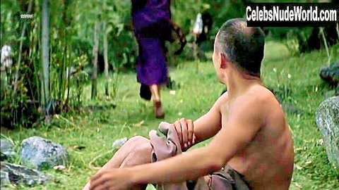 Bald muscular man sits with bare naked ass exposed outdoors as woman in purple robe walks away barefoot