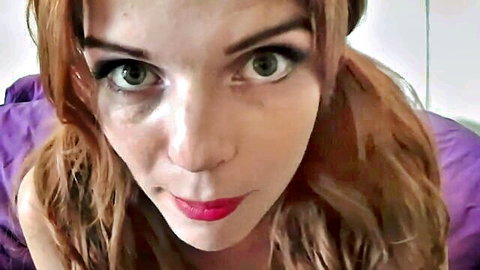 Sexy redhead with pigtails and red lips teases with wide green eyes in purple top selfie