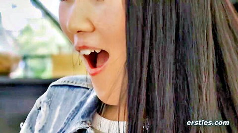 Young Asian woman with open mouth and long black hair in denim jacket