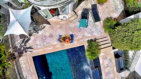 Bella Bellz lounging poolside in colorful towel, teasing outdoor vibe