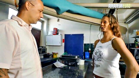 Brunette amateur in tight white tank top faces bald guy intensely in kitchen foreplay
