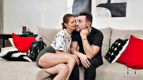Fit brunette woman kissing dark-haired man intimately on couch