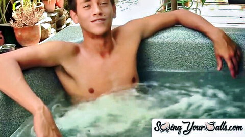 Shirtless young hunk with toned abs relaxes smiling in bubbling outdoor jacuzzi