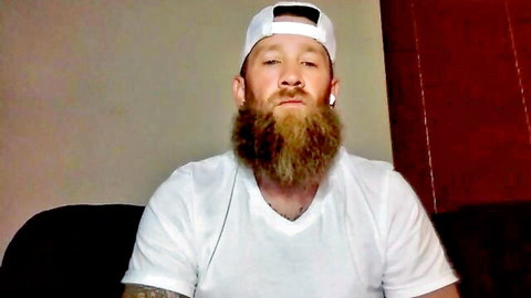 Bearded man in white cap and v-neck t-shirt on webcam solo interview