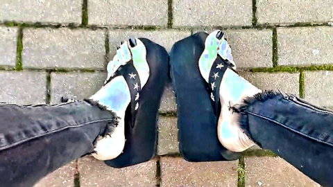 POV closeup of sexy iridescent platform high heels and ripped jeans feet on outdoor pavement