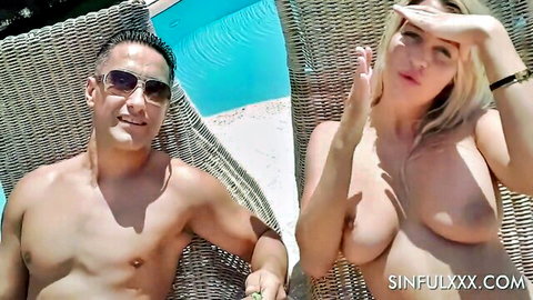 Topless blonde with big tits lounging poolside with fit shirtless man in summer vibe