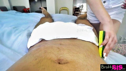 Sexy nurse in white uniform teases hairy patient's towel-covered cock with yellow sponge on bed