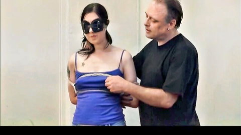 Blindfolded amateur girl bound in blue tank top, man dominating from behind
