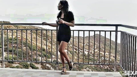 Ebony woman in sexy black mini dress on balcony overlook