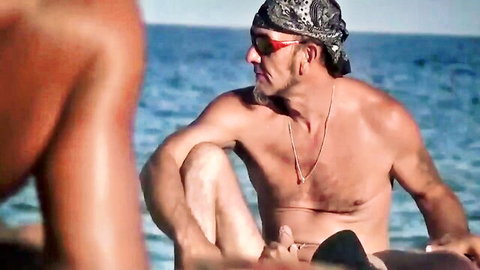 Two muscular men on sunny beach, shirtless and intimate