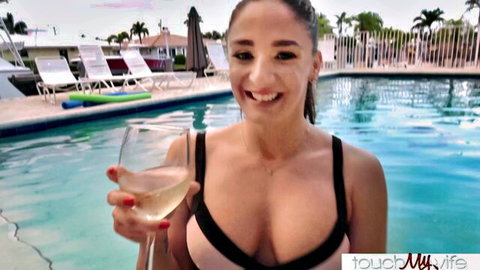 Sheena Ryder in sexy pink bikini holding wine by pool, smiling seductively