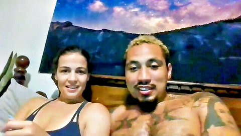 Augs420 cam couple: tattooed shirtless guy and busty brunette chilling on bed