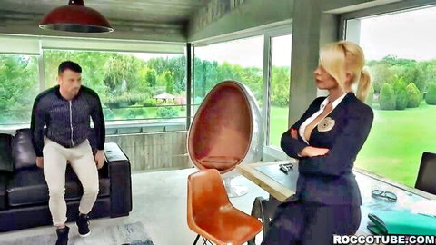 Blonde woman in blouse and skirt confronts seated man in office scene